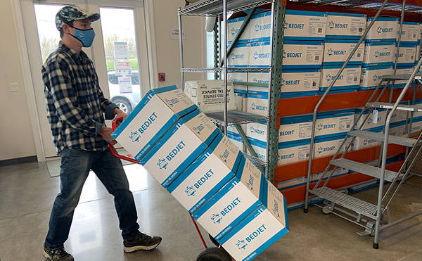 A BedJet worker moves a stack of BedJets around the warehouse on a dolly