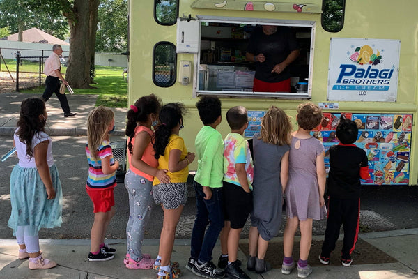 A group of young schoolchildren order ice cream from the Palagi Brothers Ice Cream Truck
