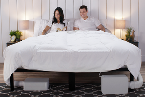 a couple smiling and reading in bed with a BedJet Dual Zone System installed